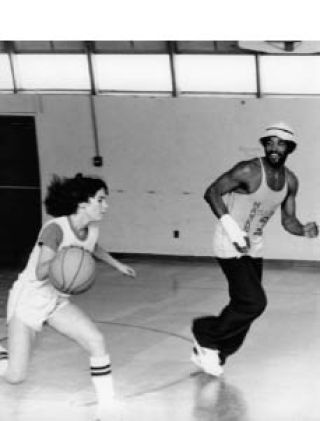 Tosha Bartholomew dribbles the ball past NBA star guard Ron Lee