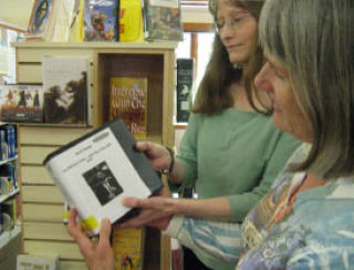 Lopez Library assistant Kathy Holliday (left) and patron Barbara Carver check out the new audio books featuring KLOI programs.