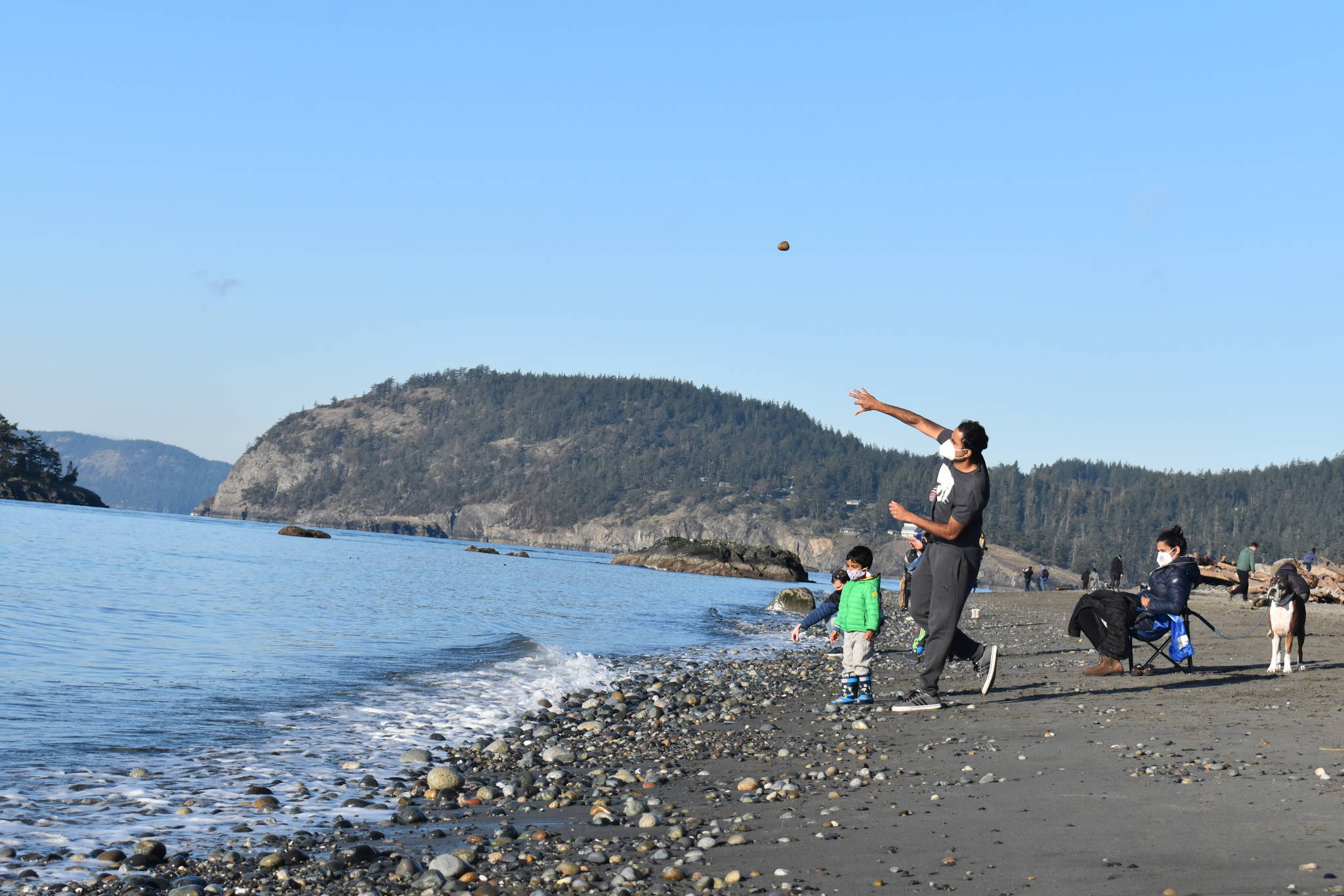 Raghu Maddirala of Bellevue and son Arjun, 3, throw rocks at West Beach in Deception Pass State Park last Saturday. The park would be used as a Navy training site along with others on Whidbey under a new five-year proposal. (Emily Gilbert/Whidbey News-Times)