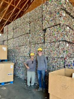 Todd Reynolds photo.
Board members John Trench (right) and Gene Helfman stand at the base of a mountain of baled aluminum cans at the Skagit River Steel and Recycling Center in Burlington. These bales are destined to become aluminum cans.