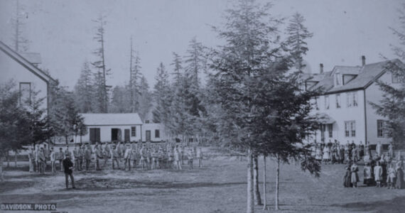 Students in cadet uniforms in front of the buildings, Indian training school, Forest Grove, Oregon,” (1882) taken from Federal Indian Boarding School Initiative Investigative Report, Volume 2.