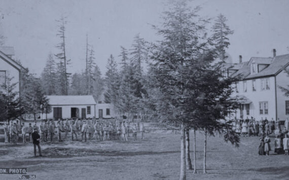 Students in cadet uniforms in front of the buildings, Indian training school, Forest Grove, Oregon,” (1882) taken from Federal Indian Boarding School Initiative Investigative Report, Volume 2.